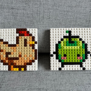 Op de afbeelding: Twee pixel art-moza&iuml;eken, een van een bruine kip en de andere van een groene appel met een gezicht. Beide zijn gemaakt van witte, bruine, groene en gele LEGO-stenen van plastic.