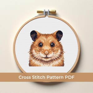May include: A cross-stitch pattern of a hamster in a wooden embroidery hoop. The hamster has brown and tan fur, black eyes, and long white whiskers. The text "Cross Stitch Pattern PDF" is displayed at the bottom.