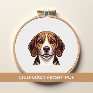 May include: A cross-stitch pattern of a beagle dog's face, framed in a wooden embroidery hoop. The dog has brown and white fur, with a detailed pixelated design. The text "Cross Stitch Pattern PDF" is displayed below the hoop.