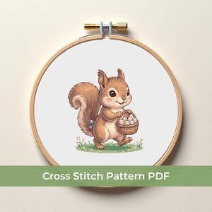 May include: A cross-stitch pattern featuring a cartoon squirrel carrying a basket of eggs. The squirrel is brown with a fluffy tail and a blue bow. The design is set in a wooden embroidery hoop, with the text "Cross Stitch Pattern PDF" at the bottom.