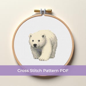 Könnte beinhalten: Ein Kreuzstichmuster mit einem Eisbären in einem hölzernen Stickrahmen. Der Bär ist weiß mit schwarzen Augen und Nase. Der Text "Cross Stitch Pattern PDF" steht auf einem lila Banner.