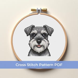 May include: A cross-stitch pattern of a Schnauzer dog, displayed in a wooden embroidery hoop. The dog is rendered in shades of gray and white, with a detailed pixelated design. The text "Cross Stitch Pattern PDF" is displayed below the image.
