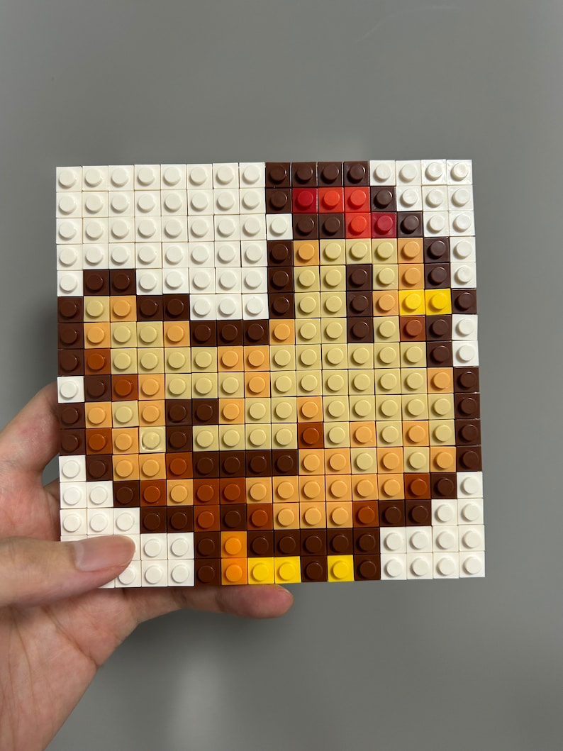 Op de afbeelding: Een pixel art-moza&iuml;ek van een bruine en gele kip gemaakt met kleine vierkante plastic blokken. De kip kijkt naar rechts en heeft een rode kam.