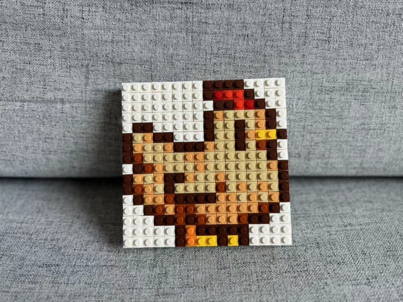 Op de afbeelding: Een bruine en gele kip gemaakt van Lego-stenen. De kip staat op een witte basis.