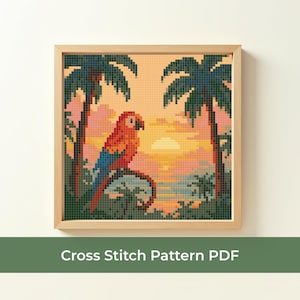 May include: Cross stitch pattern featuring a vibrant parrot on a branch, set against a sunset with palm trees. The artwork is framed in a light wood frame. The text "Cross Stitch Pattern PDF" is at the bottom.