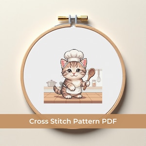 May include: A cross-stitch pattern in a wooden hoop features a cartoon cat chef holding a wooden spoon. The cat wears a chef's hat and apron, standing in a kitchen setting. The text "Cross Stitch Pattern PDF" is displayed below the hoop.