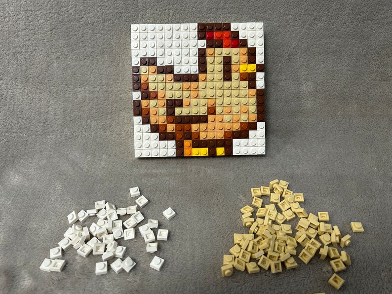 Op de afbeelding: Een close-up van een moza&iuml;ek van een kip gemaakt met kleine plastic blokken. De kip is bruin, geel en rood. Er zijn stapels witte en lichtbruine blokken onder het moza&iuml;ek.