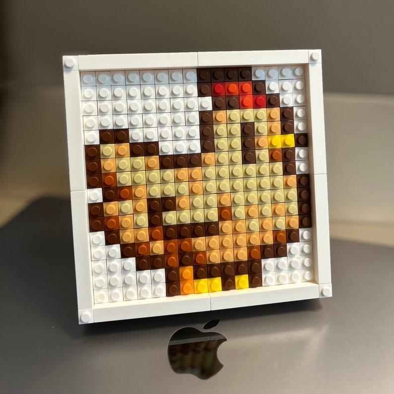 Op de afbeelding: Een wit frame met een moza&iuml;ek van kleurrijke plastic vierkanten die een kip voorstellen. De kip is bruin, geel en oranje.