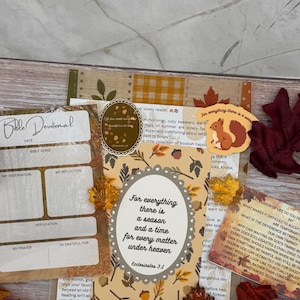 May include: A collection of autumn-themed stationery including a Bible Devotional sheet, a card with the text For everything there is a season and a time for every matter under heaven, a squirrel sticker, and several decorative fabric maple leaves.