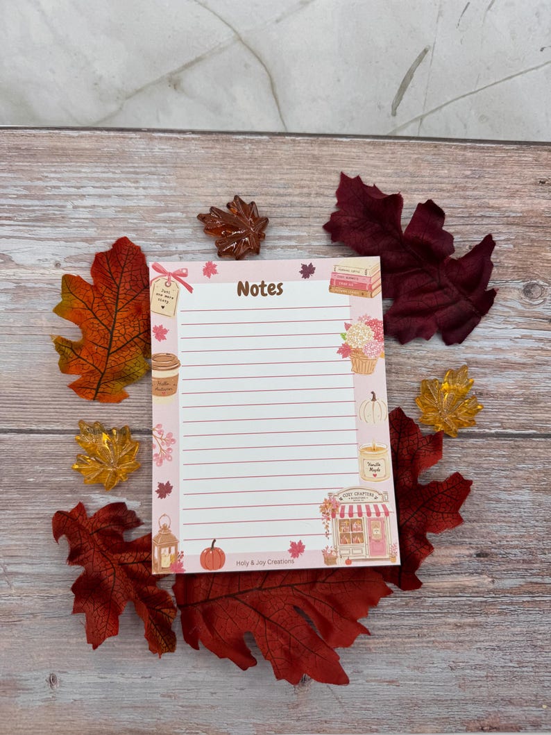 Peut inclure: Un bloc-notes rectangulaire avec des lignes horizontales et le mot Notes en haut. La bordure pr&eacute;sente des illustrations d'une tasse de caf&eacute;, d'une citrouille, d'une bougie, d'une lanterne, d'une librairie et de feuilles d'automne. Le texte Holy & Joy Creations est en bas.
