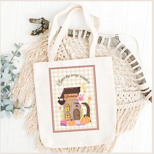 Peut inclure: Un sac fourre-tout crème avec une illustration fantaisiste. Le motif représente une maison violette et marron avec le texte "Spooky cozy reader Bookstore". Des citrouilles, un fantôme et un croissant de lune complètent le design. Le sac a des anses crème.