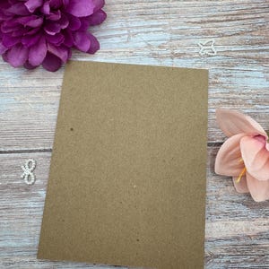 Peut inclure: Une feuille de papier cartonn&eacute; kraft marron de forme rectangulaire plac&eacute;e au centre. Ce papier cartonn&eacute; pr&eacute;sente une texture lisse et mate ainsi qu'une couleur marron uniforme sur toute sa surface, offrant un espace vierge pour divers projets.