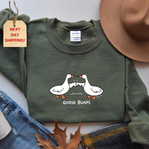 May include: A green sweatshirt with a white goose design and the text "Goose Bumps".