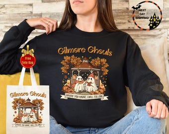 May include: Black sweatshirt with "Gilmore Ghouls" text and a graphic of two ghosts in a gazebo with pumpkins. A white tote bag with the same design is visible. The image includes a "Free Tote Bag" tag and a "Next Day Shipping!" graphic.