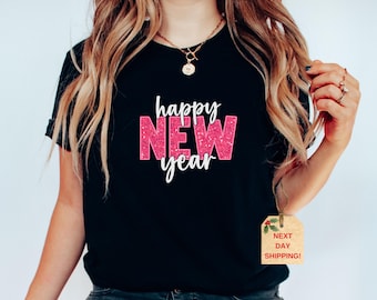 May include: Black t-shirt with the text "happy new year" in pink glitter letters. The word "new" is larger than the other words.