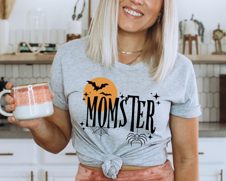 May include: Gray t-shirt with a black and orange graphic design featuring a spider, bats, and the text "MOMSTER".
