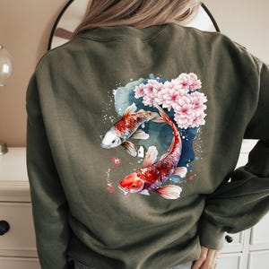 Puede incluir: Una sudadera verde con un dise&ntilde;o de acuarela de dos peces koi nadando entre flores de cerezo rosas.