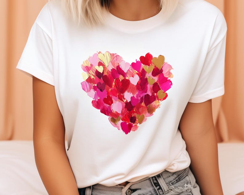 Op de afbeelding: Wit T-shirt met een groot hartontwerp gemaakt van veel kleine roze, rode en gouden hartjes.