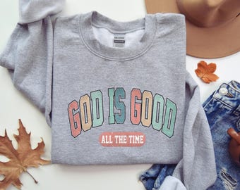 May include: A gray sweatshirt with the text "God is Good" in rainbow colors with the words "All the Time" underneath.