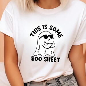 May include: White t-shirt with a black and white graphic of a ghost wearing sunglasses and the text "This is some boo sheet".