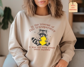 May include: A tan sweatshirt with a raccoon holding a lemon and the text "in the interest of full transparency it was not easy peasy lemon squeezy".