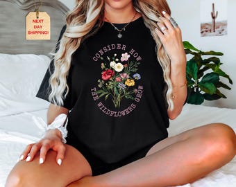 May include: Black t-shirt with a floral graphic and the text "Consider How The Wildflowers Grow".
