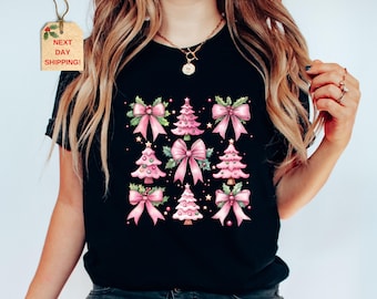 May include: Black t-shirt with a pink and green Christmas tree design. The trees are decorated with pink bows and ornaments. The text "Next Day Shipping!" is on a brown tag.