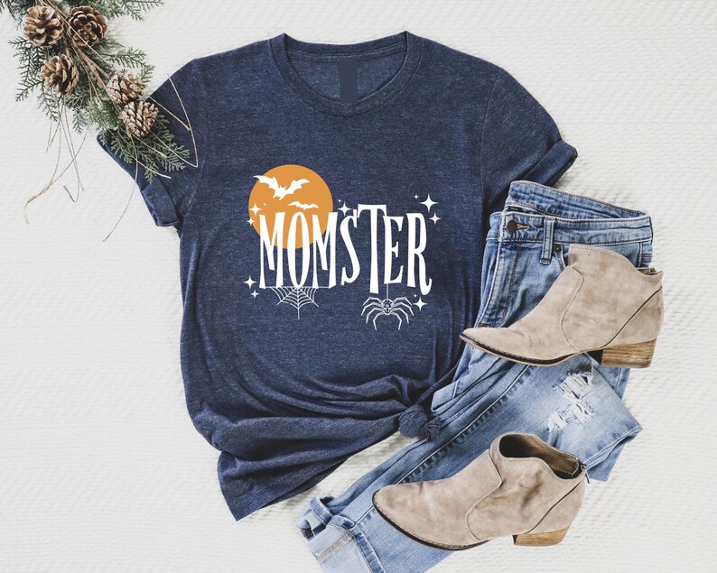May include: A navy blue t-shirt with a white graphic design featuring a spider, bats, and a moon with the text "MOMSTER".