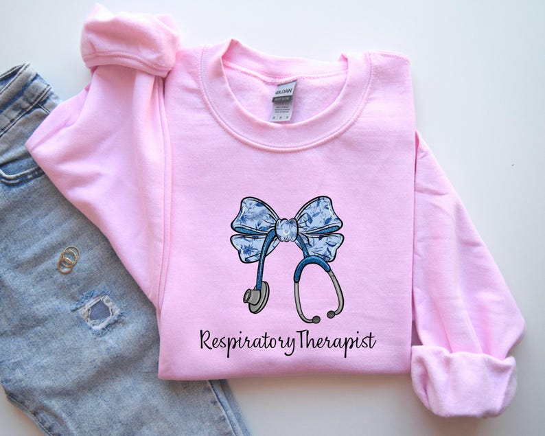 May include: Pink sweatshirt with a blue and white bow and stethoscope graphic. The text "Respiratory Therapist" is printed below the graphic.