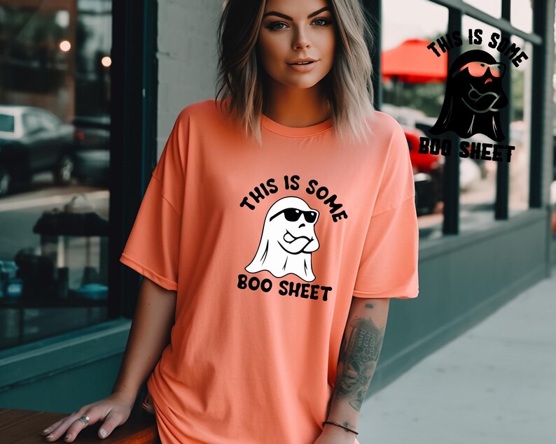 May include: A coral orange t-shirt with a white ghost wearing sunglasses and the text "This is some boo sheet".