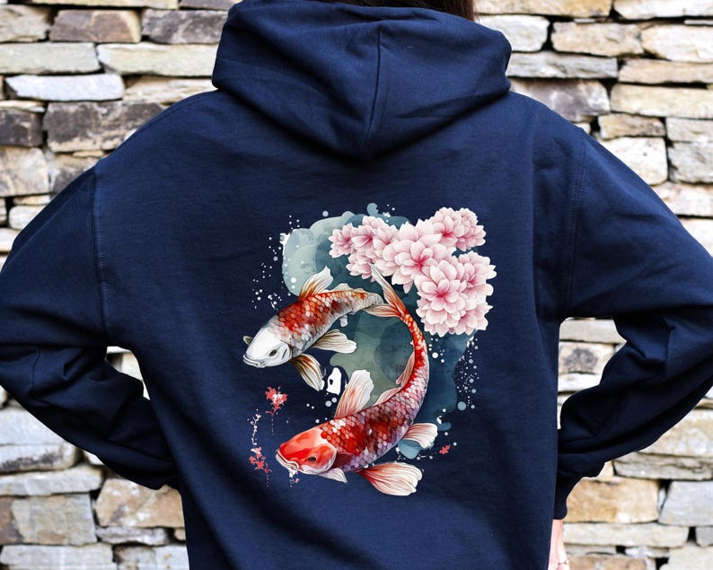 Puede incluir: Una sudadera con capucha azul marino con un dise&ntilde;o de acuarela de dos peces koi nadando entre flores de cerezo rosas.