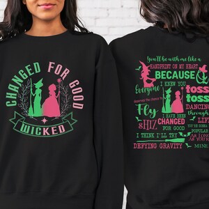May include: Black sweatshirt with a green and pink graphic of two witches and the text "Changed for Good Wicked". The back of the sweatshirt has pink and green text that reads "You'll be with me like a handprint on my heart because I knew you everyone deserves the chance to fly shiz changed for good I think I'll try defying gravity toss toss dancing through life you're gonna be popular as long as you're mine."