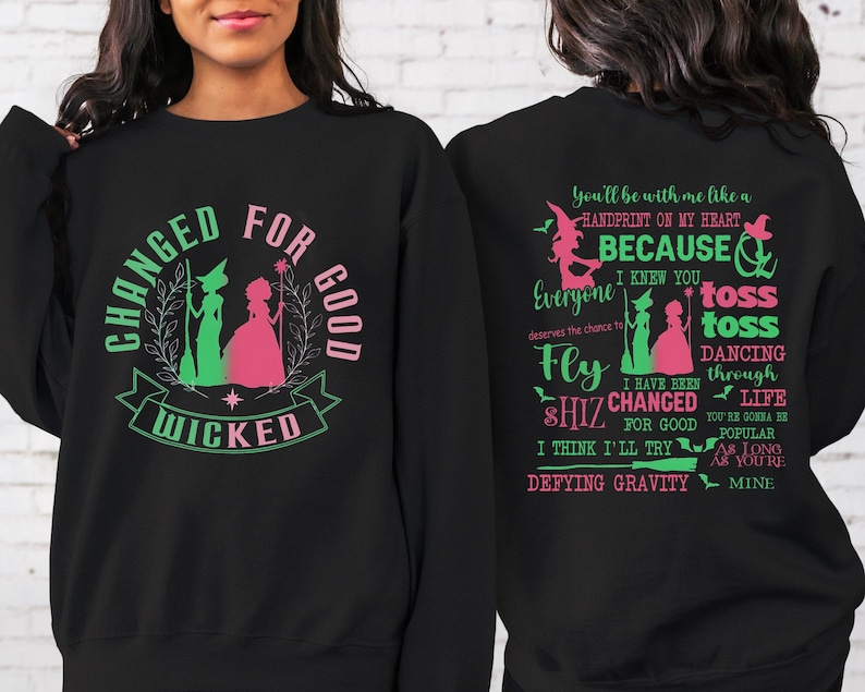 May include: Black sweatshirt with a green and pink graphic of two witches and the text "Changed for Good Wicked". The back of the sweatshirt has pink and green text that reads "You'll be with me like a handprint on my heart because I knew you everyone deserves the chance to fly shiz changed for good I think I'll try defying gravity toss toss dancing through life you're gonna be popular as long as you're mine."
