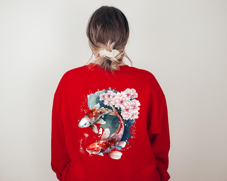 Puede incluir: Sudadera roja con un dise&ntilde;o de acuarela de dos peces koi nadando en un estanque con flores rosas.
