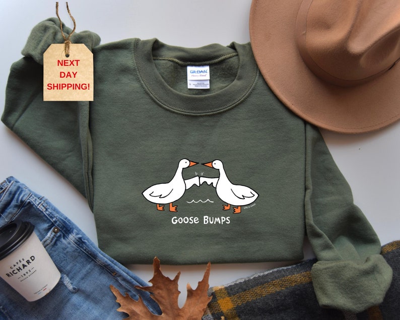 May include: A green sweatshirt with a white goose design and the text "Goose Bumps".