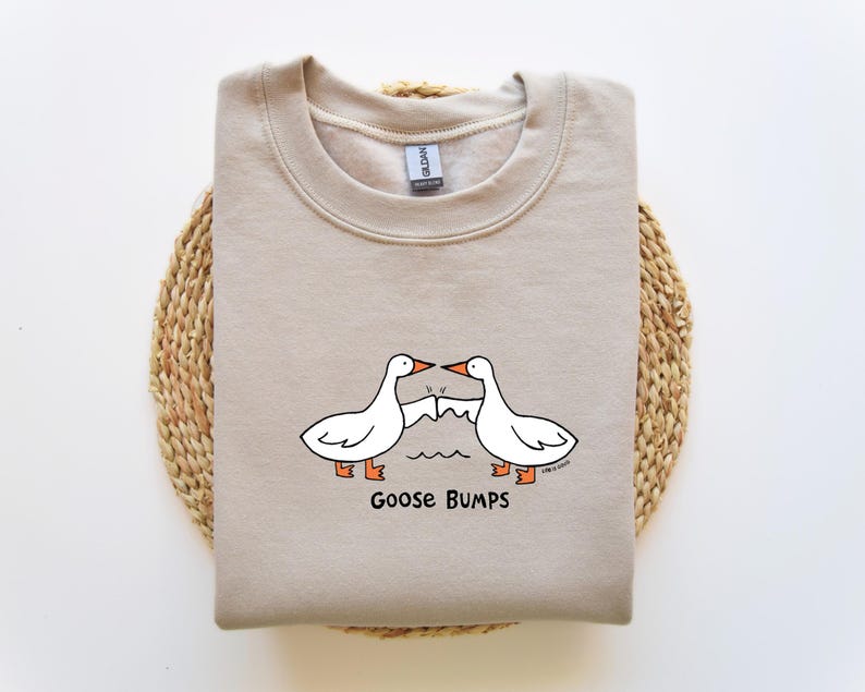 May include: A beige sweatshirt with a graphic of two geese bumping into each other. The text "Goose Bumps" is printed below the geese.