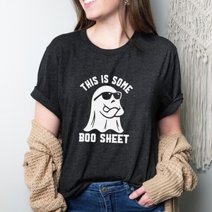 May include: A dark gray t-shirt with a white ghost wearing sunglasses and the text "This is some boo sheet".