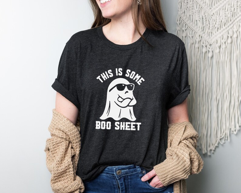 May include: A dark gray t-shirt with a white ghost wearing sunglasses and the text "This is some boo sheet".