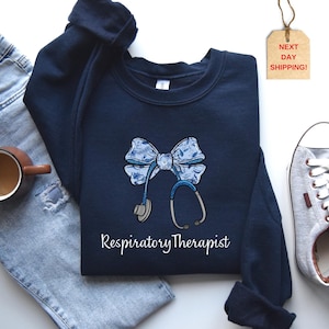 May include: Navy blue sweatshirt with a white and blue bow and stethoscope graphic. The text "Respiratory Therapist" is printed below the graphic.