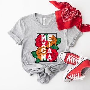 May include: A light gray t-shirt with the word "MEXICANA" in white letters, framed by red and orange roses and green leaves. A red bandana and red sneakers complete the look.