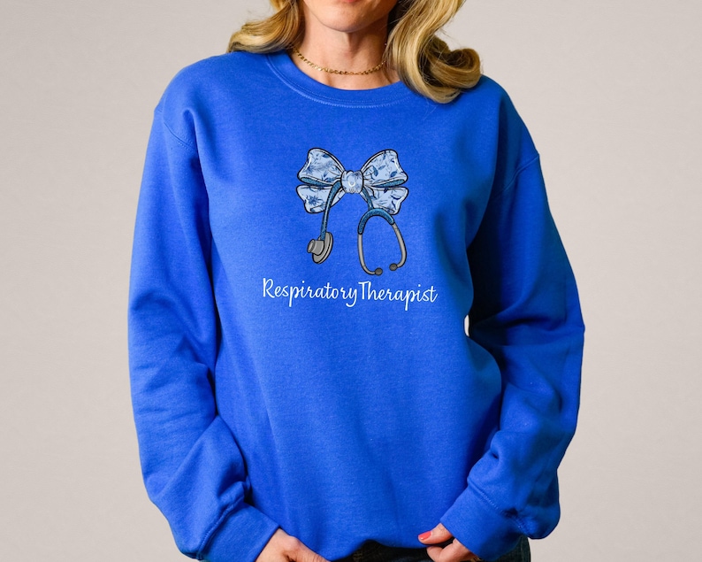 May include: Royal blue sweatshirt with a white bow and stethoscope design. The text "Respiratory Therapist" is printed below the design.