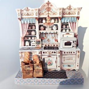 May include: A miniature white kitchen set with a white oven, a stovetop, and a cabinet with shelves. The cabinet has a pink and blue curtain and a box of Kellogg's Corn Flakes. Two brown paper bags with the text "Carl's Donuts" are on the counter with baguettes inside.