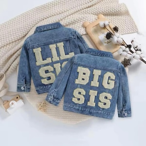 May include: Two denim jackets with embroidered patches on the back. One jacket says "Lil Sis" and the other says "Big Sis".