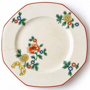 May include: An octagonal ceramic plate with a cream-colored base and a thin red rim. The surface features floral motifs in orange, yellow, blue, and green, including large orange blossoms, yellow chrysanthemums, and small blue flowers.