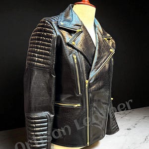 May include: Black leather motorcycle jacket with a textured, crocodile-like pattern. Features a classic asymmetrical zipper, multiple zippered pockets, and quilted shoulder and elbow detailing. Gold-toned zippers and hardware add contrast.