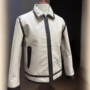 Pode incluir: Uma jaqueta de couro branca com detalhes pretos e fecho de zíper. A jaqueta tem um padrão de couro de crocodilo.