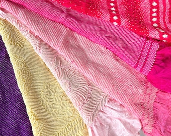 May include: Close-up of colorful textiles in shades of purple, yellow, pink, and red. The fabrics have textured patterns and varying designs, including geometric and floral motifs. The image showcases a variety of textures and colors.