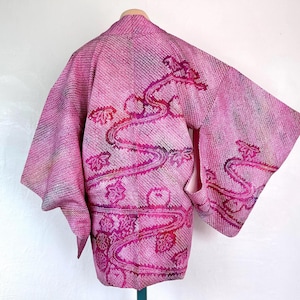 Może przedstawiać: Różowo-biały japoński kimono z kwiatowym wzorem. Kimono jest wykonane z miękkiej, lekkiej tkaniny i ma tradycyjny wzór.