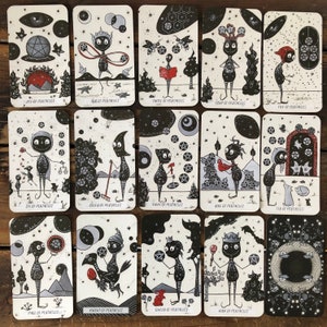 May include: A set of 14 tarot cards featuring black and white illustrations of figures with pentacles. The cards are part of a tarot deck with a whimsical and dark aesthetic.