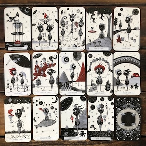 May include: A set of 14 tarot cards featuring black and white illustrations of whimsical characters with cups. The cards are numbered from Ace to King and include a Knight and Queen card. The cards are part of a tarot deck.
